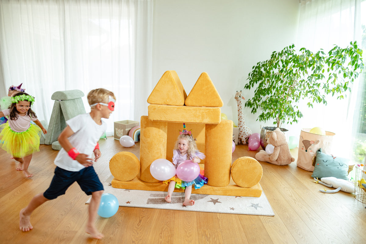 Mädchen als Einhorn verkleidet sitzt in Linolino Spielsofa Burg  in Gänseblümchen Gelb